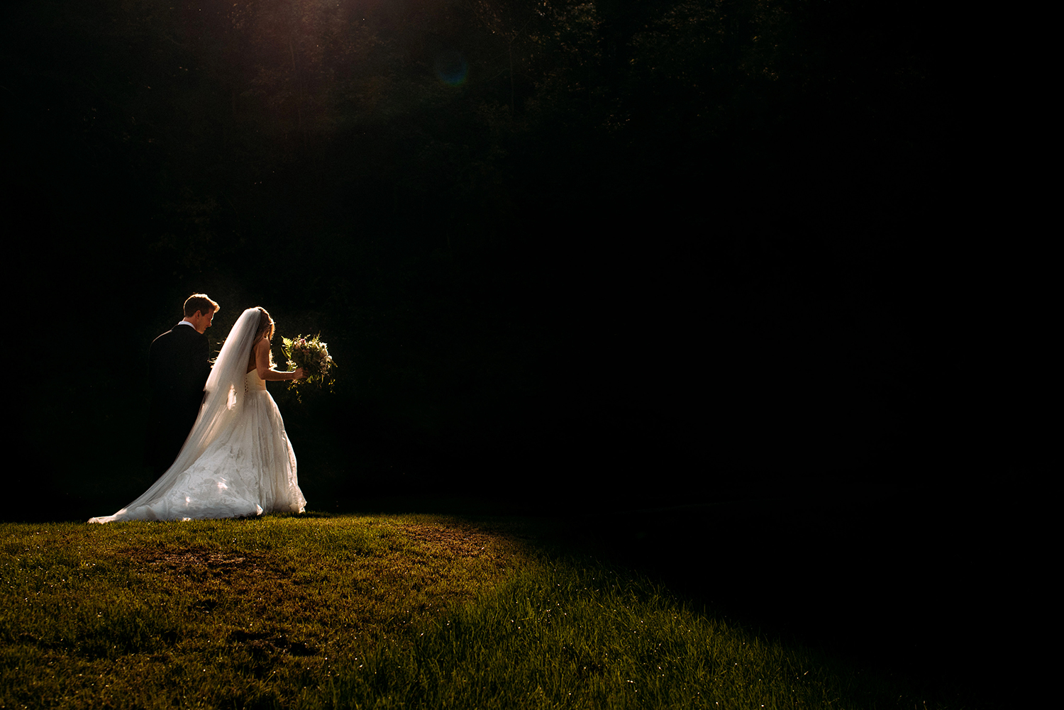  bride and groom walking through nice light into a darker area 