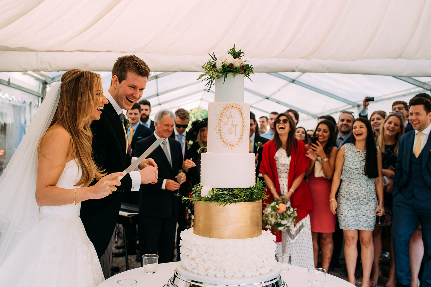  guest look on and laugh as they cut the cake 