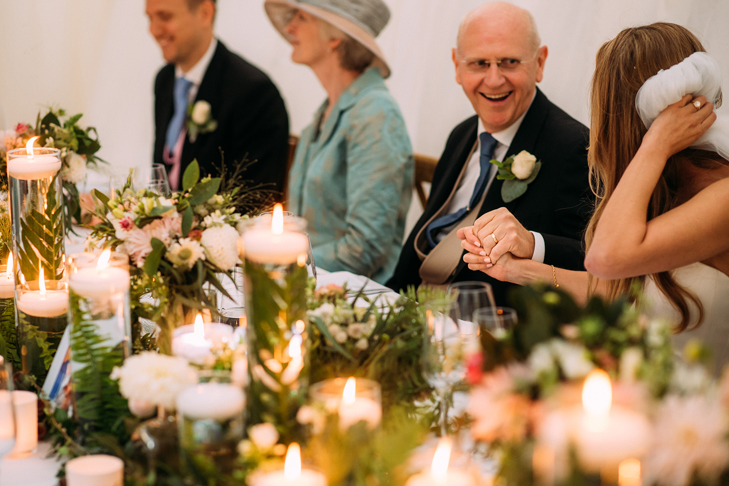 bride and father smile at each other and hold hands
