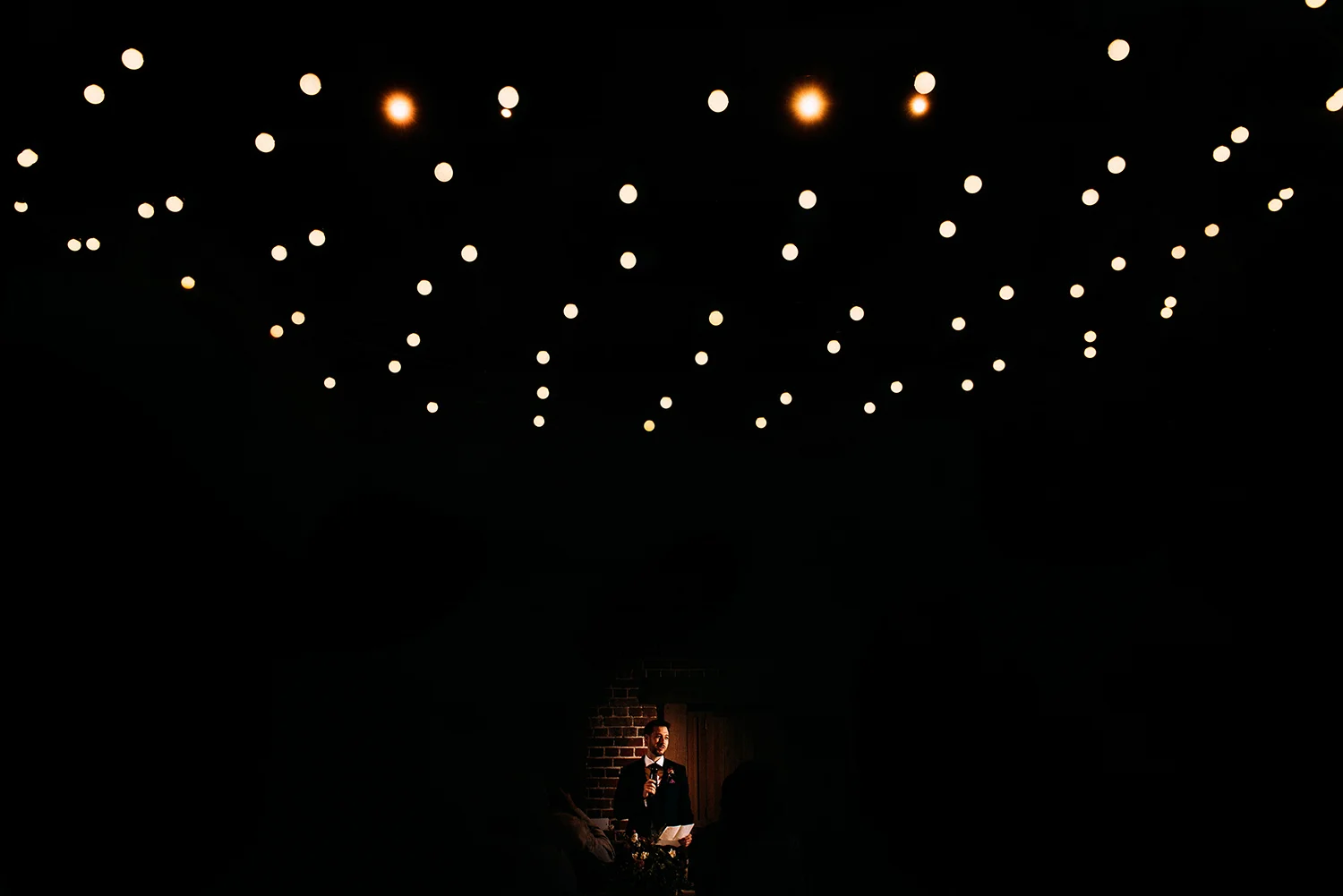 groom lit up under lights during his speech