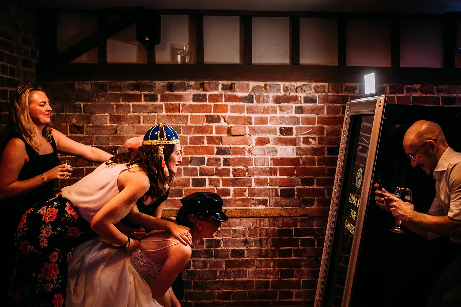 side view of the bride and her friends having a laugh in the photo booth