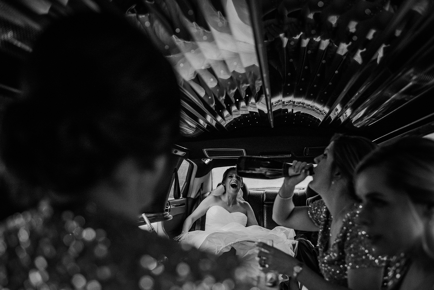 bw photo of bride laughing at her sister in the limo