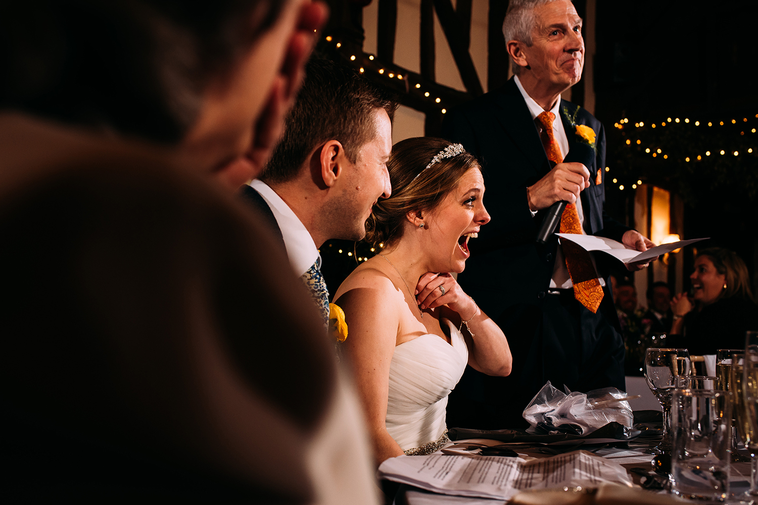 bride laughing as her father gives his speech
