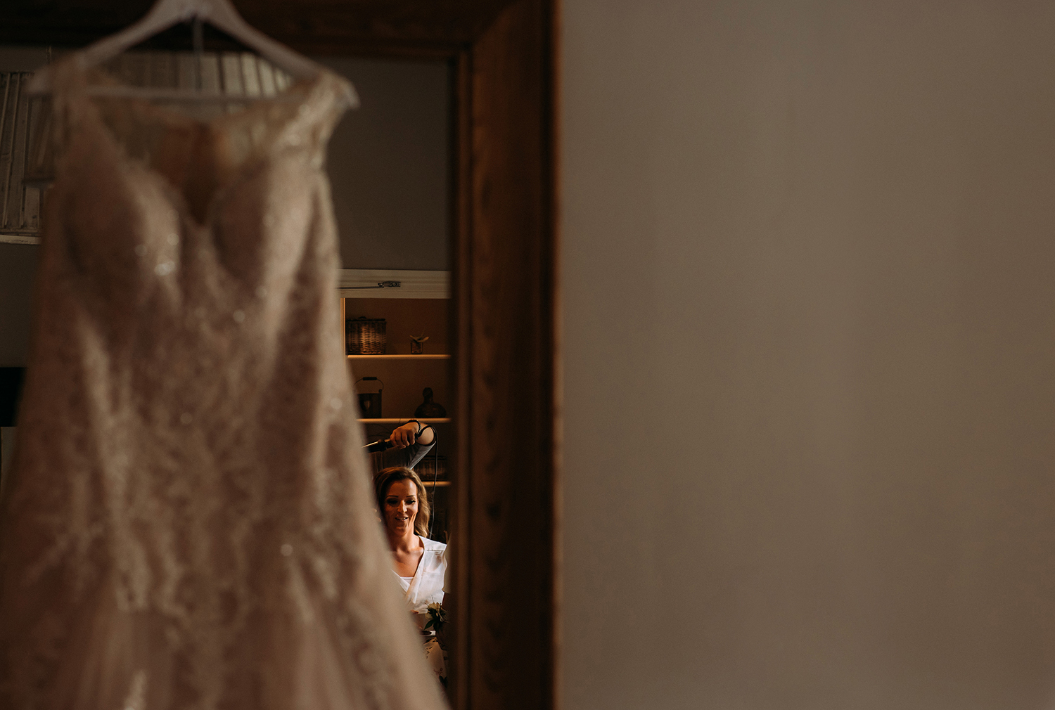 brides refection in the mirror behind the hanging wedding dress