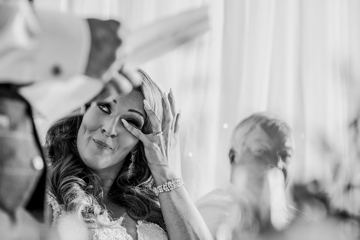 bw photo of the bride wiping a tear during the groom speech