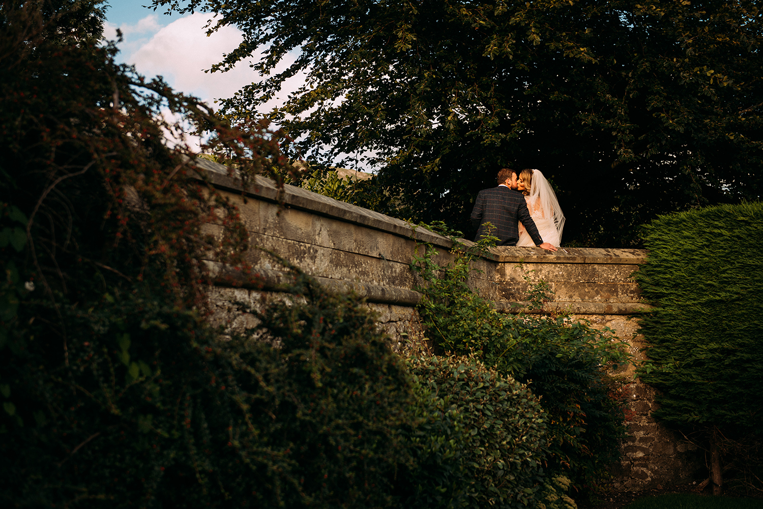 bride and groom kissing on a wall