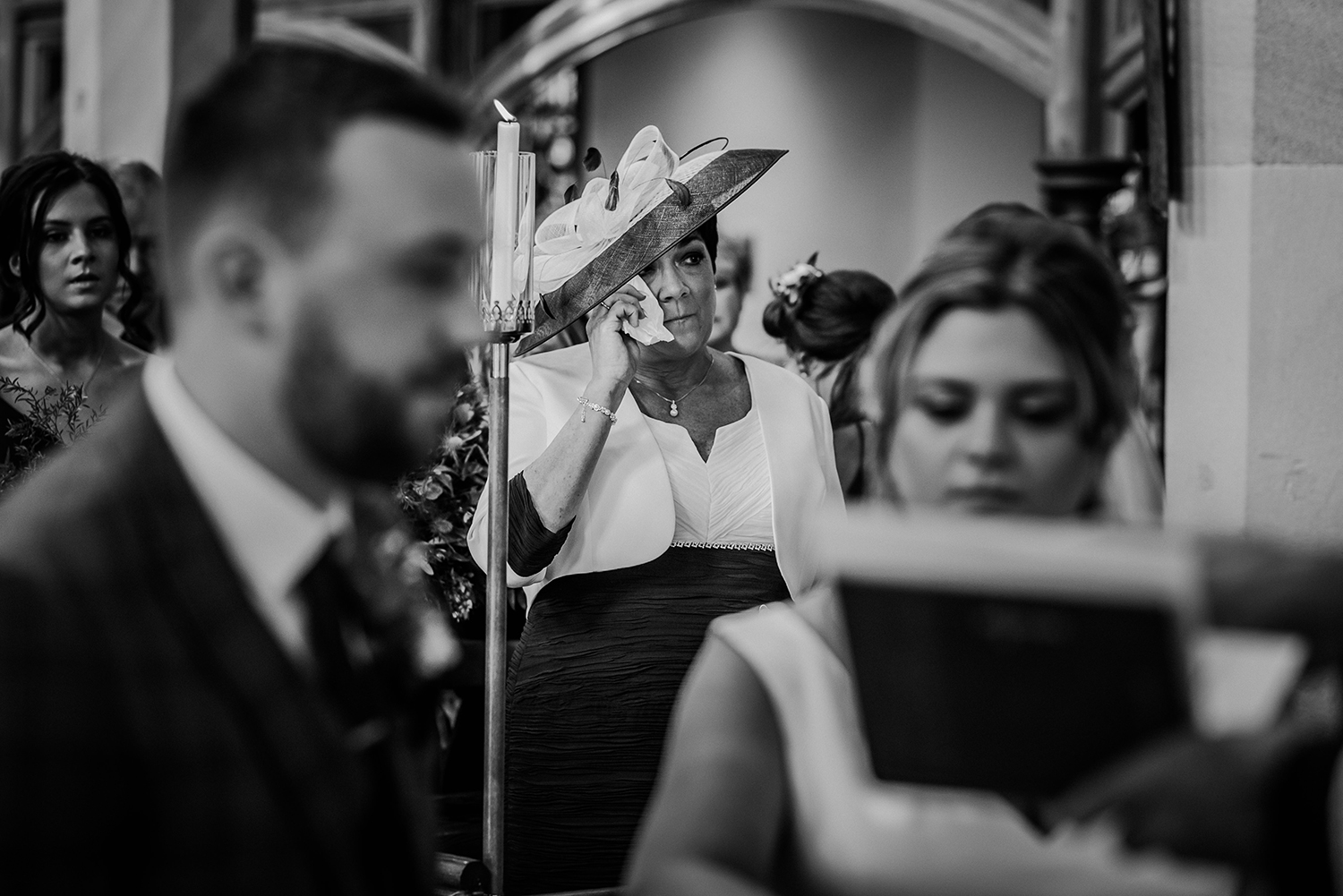 bw photo of brides mum wiping a tear in church