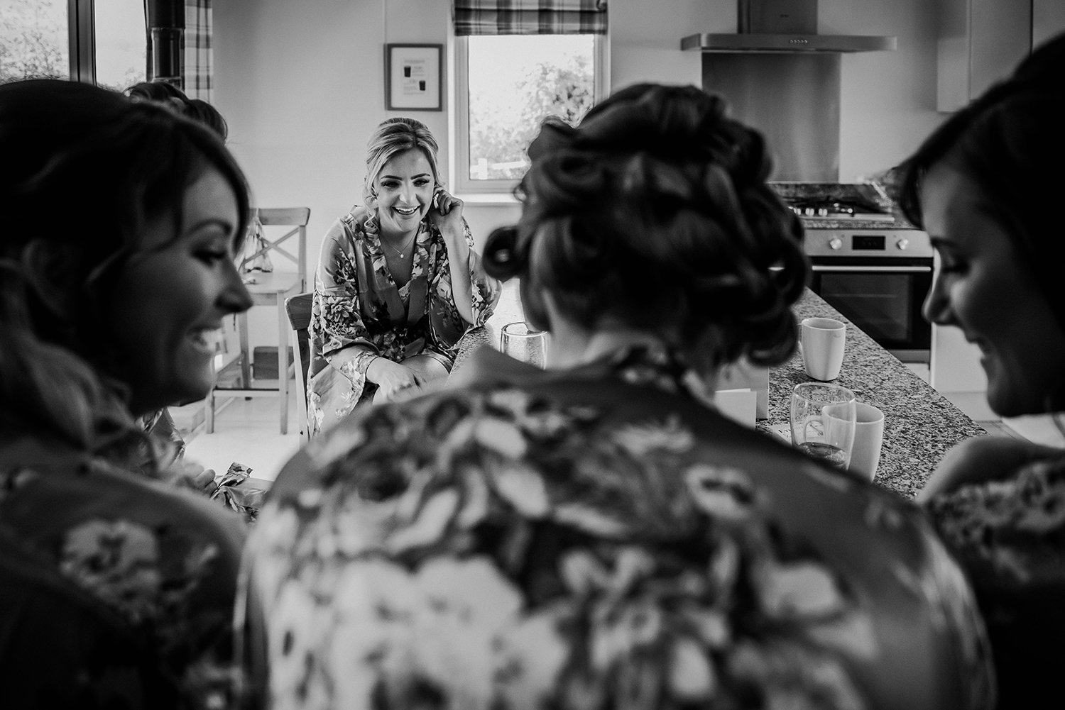 BW photo of the bridesmaids having a laugh in the kitchen