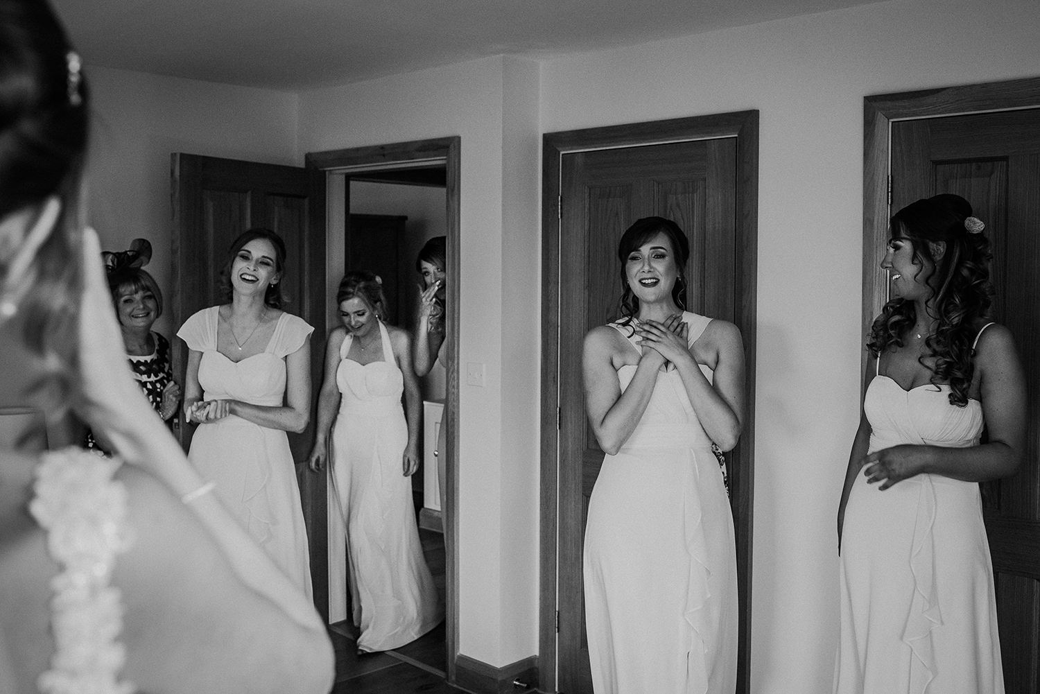 bw photo of the bridesmaids reaction to the bride in her dress