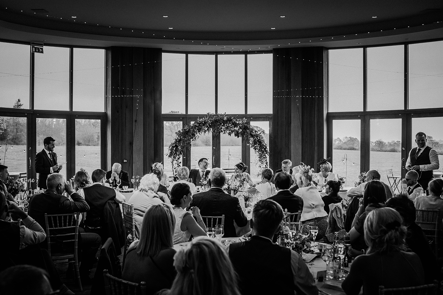 Wide BW shot of the Out Barn ceremony room during the best men speech