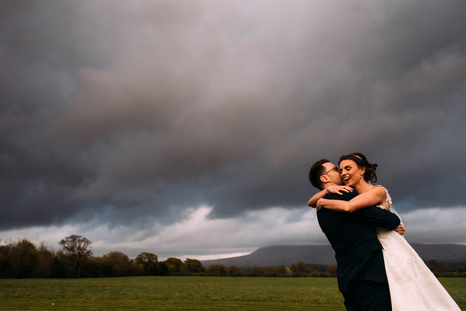 Bride and groom at the Out Barn with Pendle hill in the background.