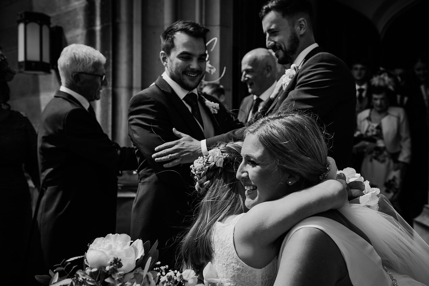 bw photo of bride and groom hugging guests