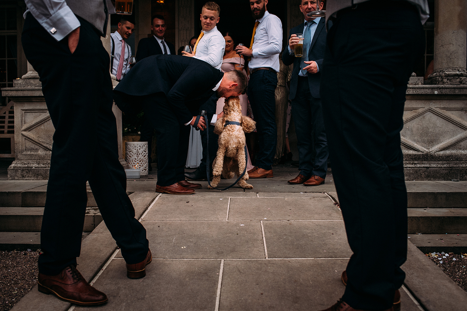 groomsman being licked in the face by a dog