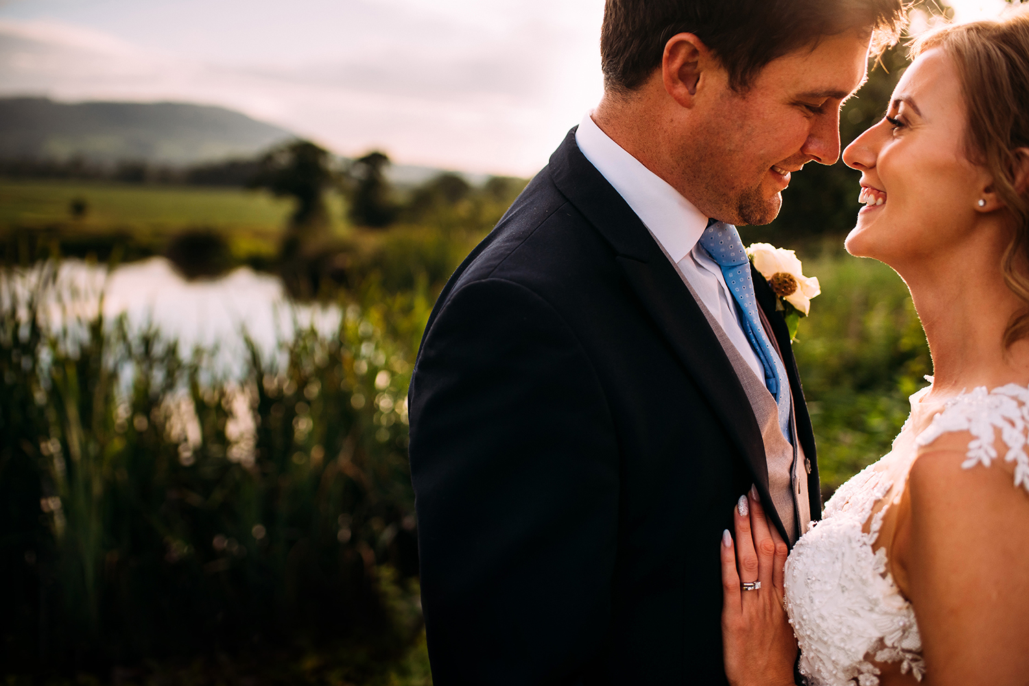 bride and groom by the water in sunlight