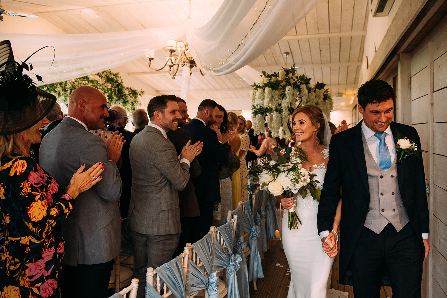 bride and groom leave the ceremony at Bashall Barn