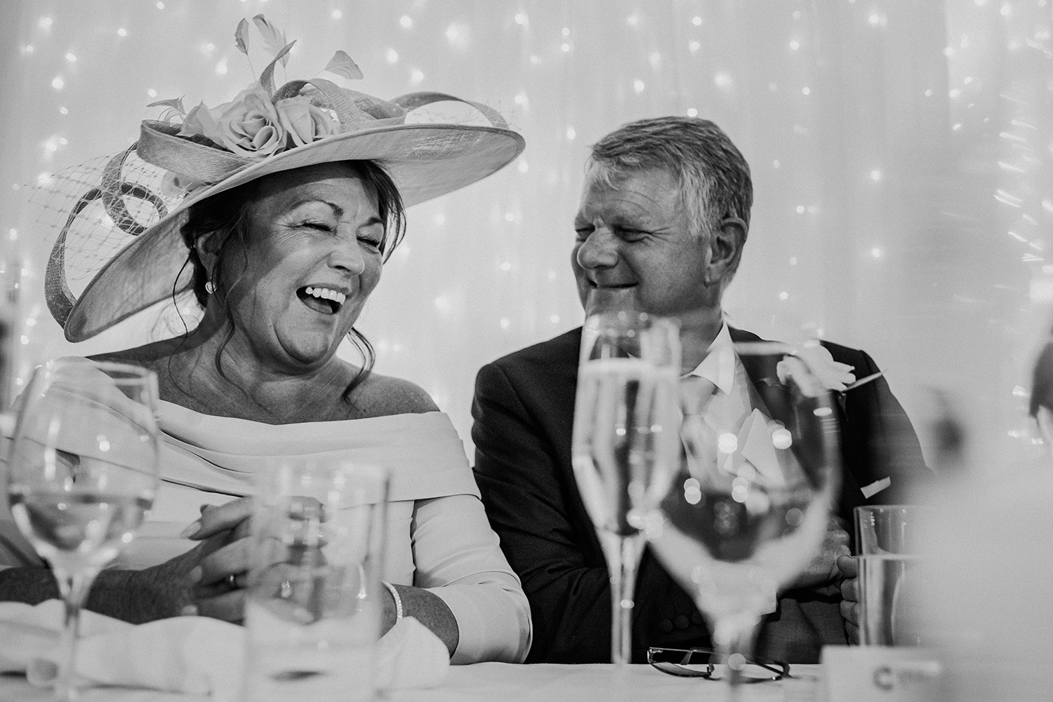 bw photo of brides father and grooms mother laughing at Bashall Barn