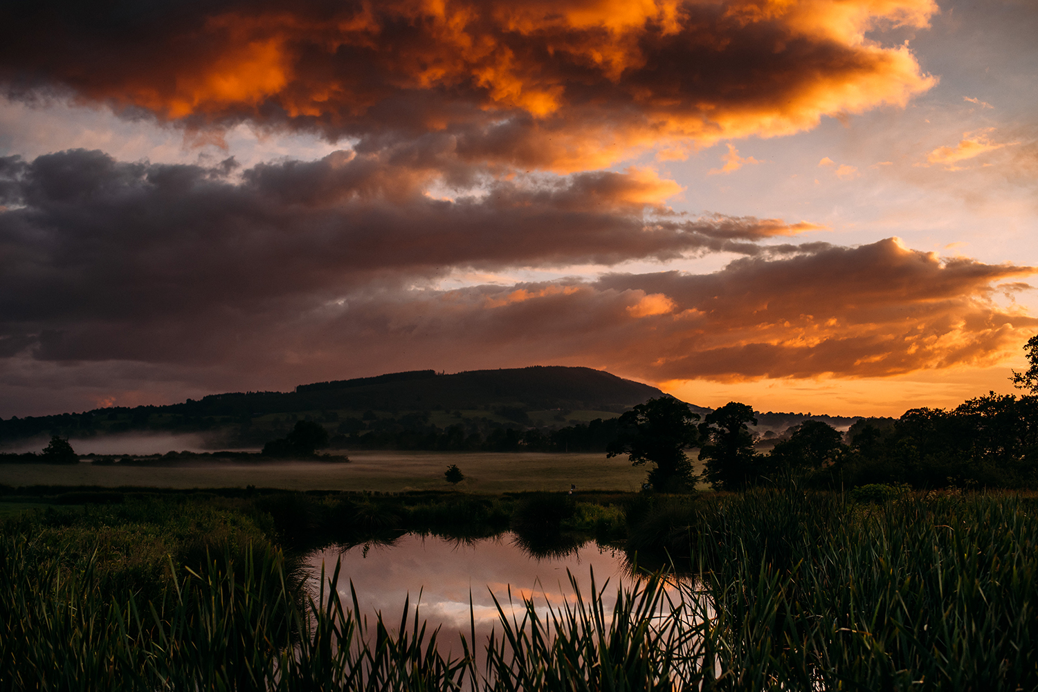 sun sets over the water and hills