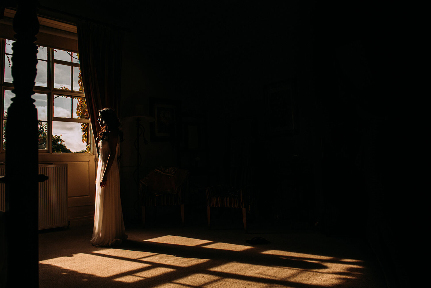  bride stood in a patch of light by the window 