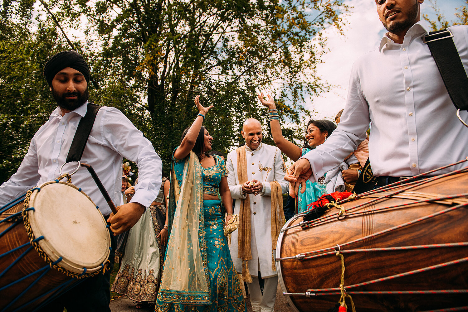  Groom and guests dancing between drums on the way to the Indian wedding ceremony 