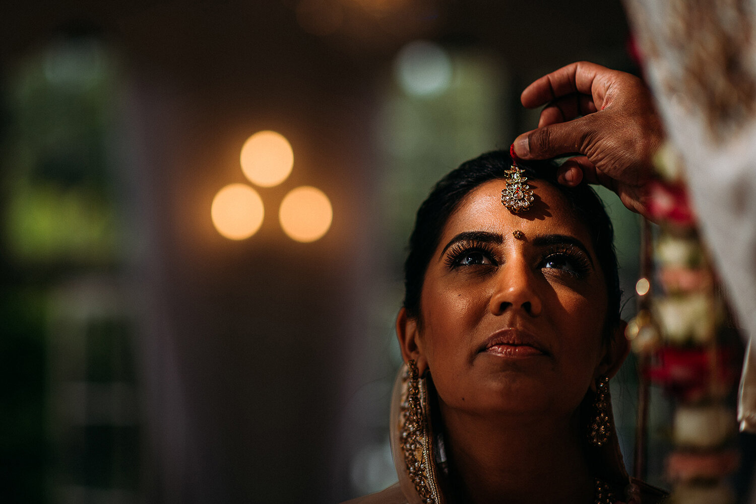  close up of the celebrant putting the red powder on the brides forehead, really nice light landing right on her eyes 