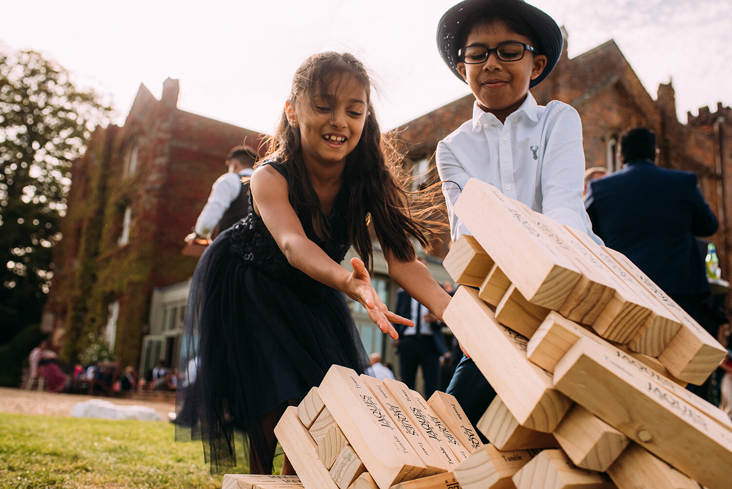  kids playing giant jenga, bricks toppling over 