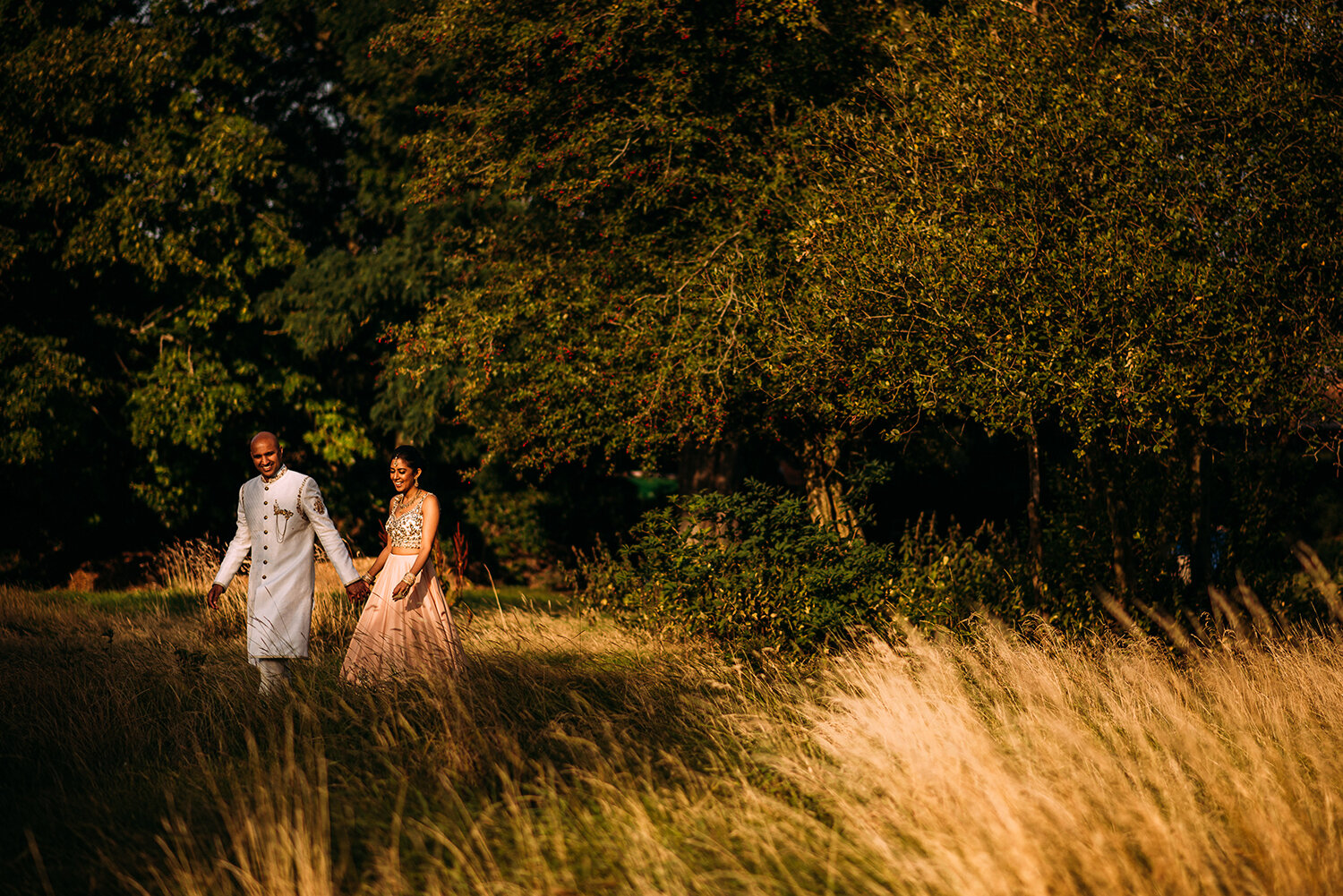  bride and groom walking through the grass 