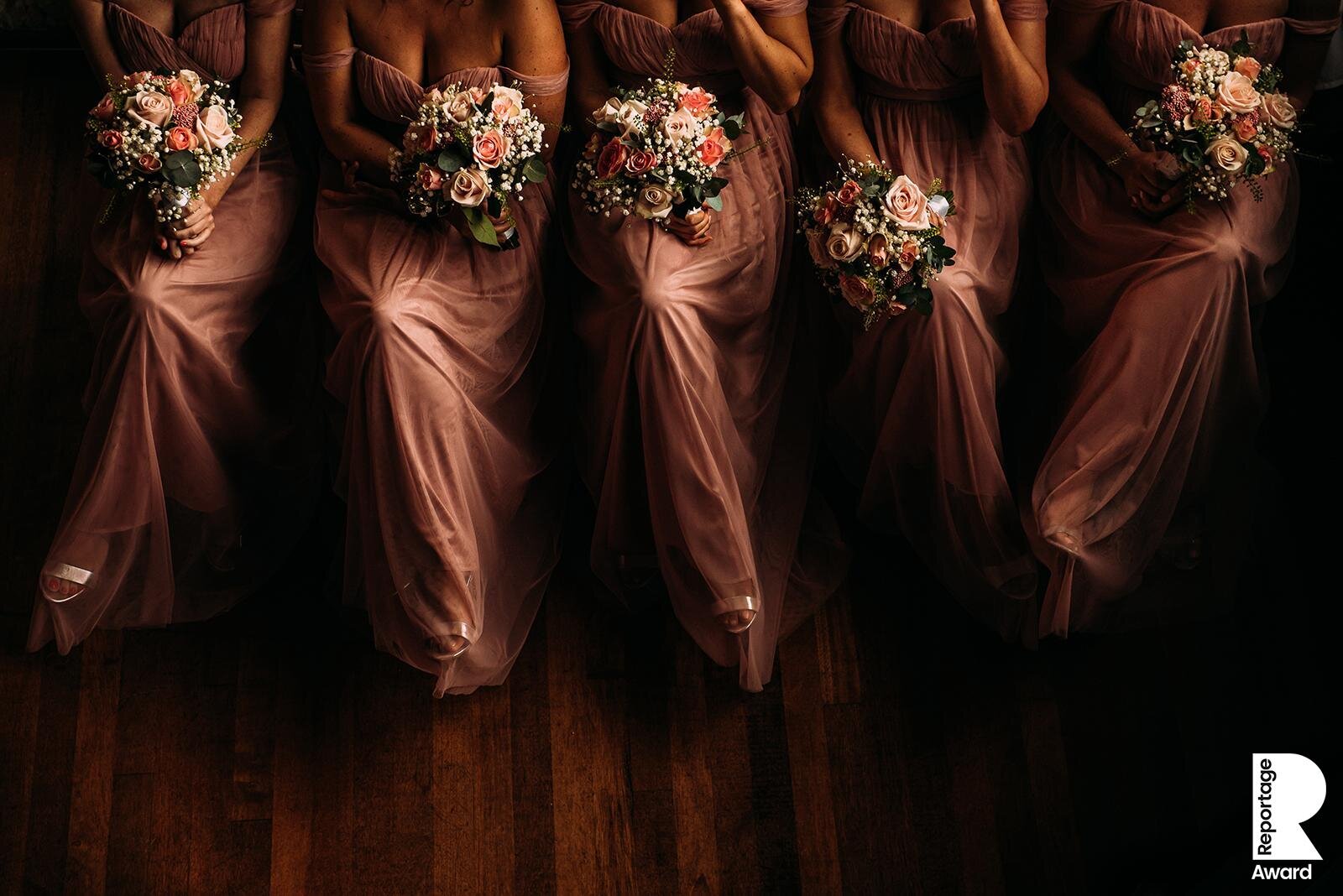  bridesmaids sat in a row with flowers on their laps 