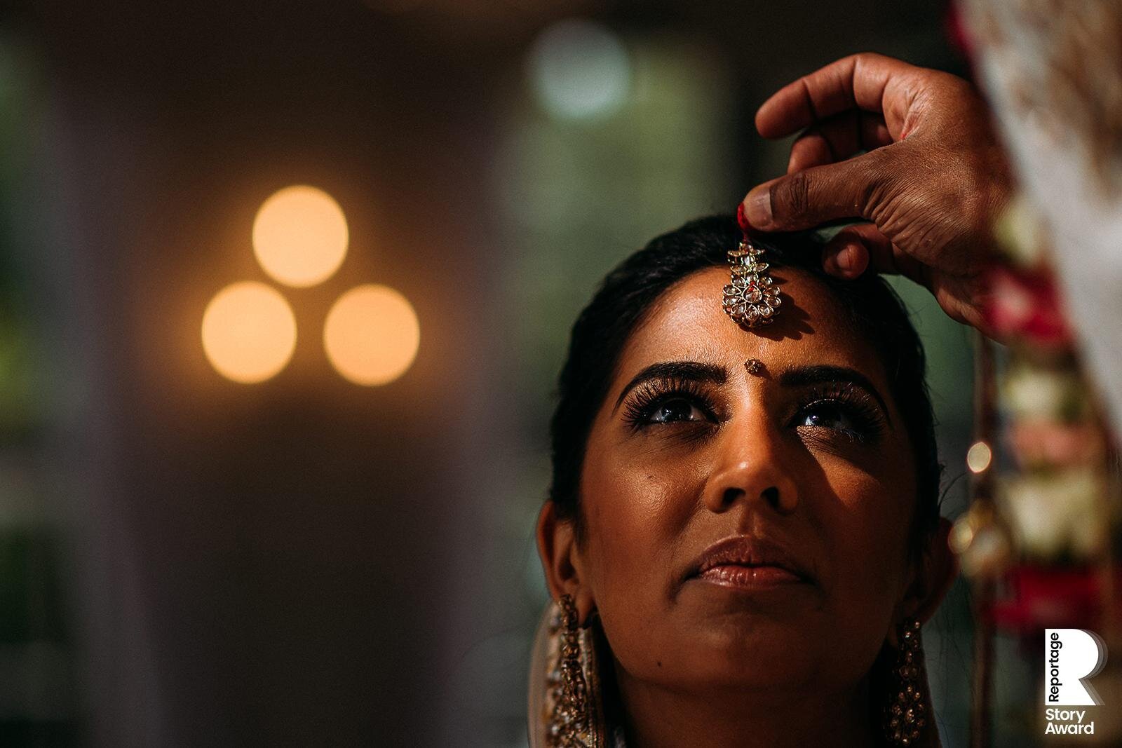  Close up of bride having red powder put on her head. 