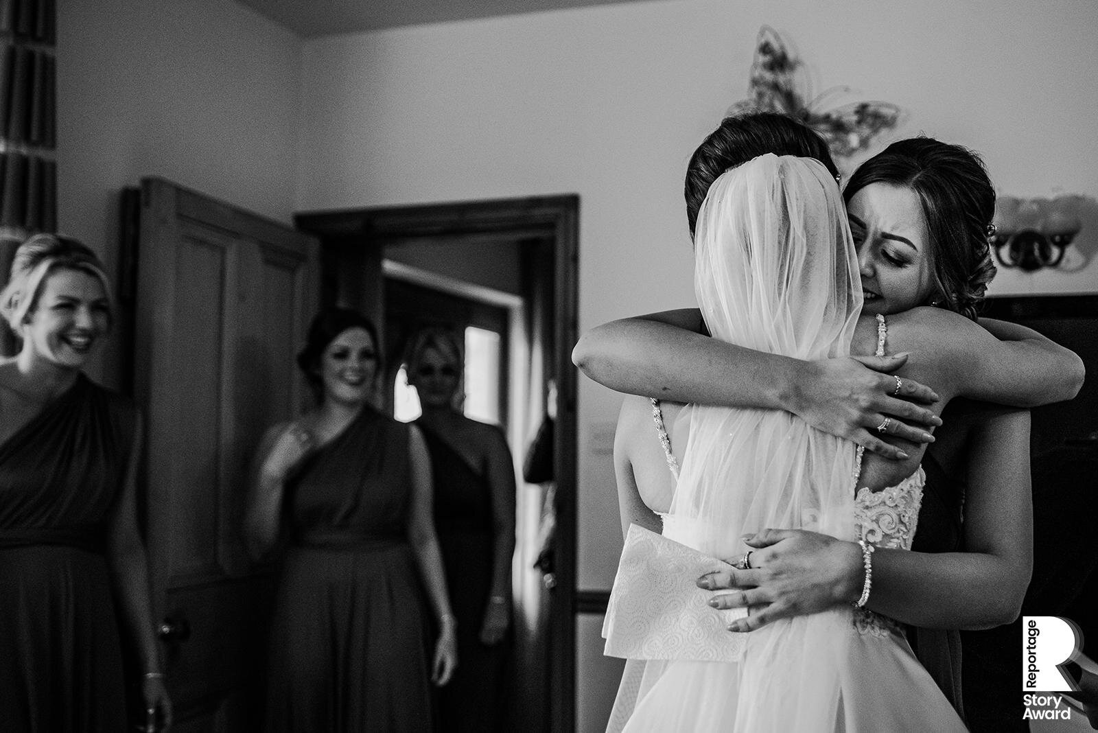  Bride and bridesmaid hugging. 
