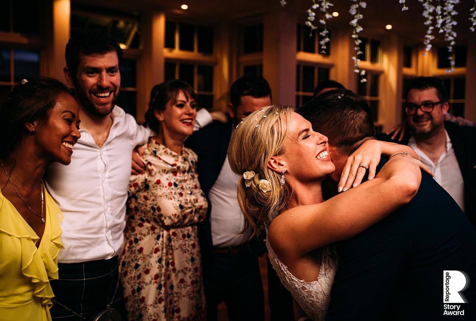  Bride and groom hugging with friends at end of the night. 
