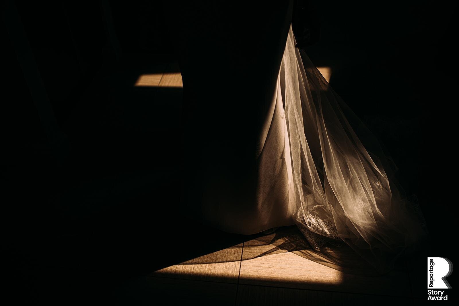  Botton of brides dress in a pocket of strong light.  