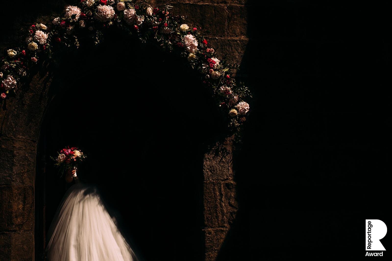  bride walking out of church. Light hitting her flowers 