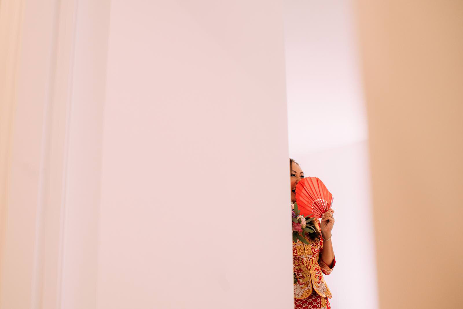 chinese bride laughing from behind a fan