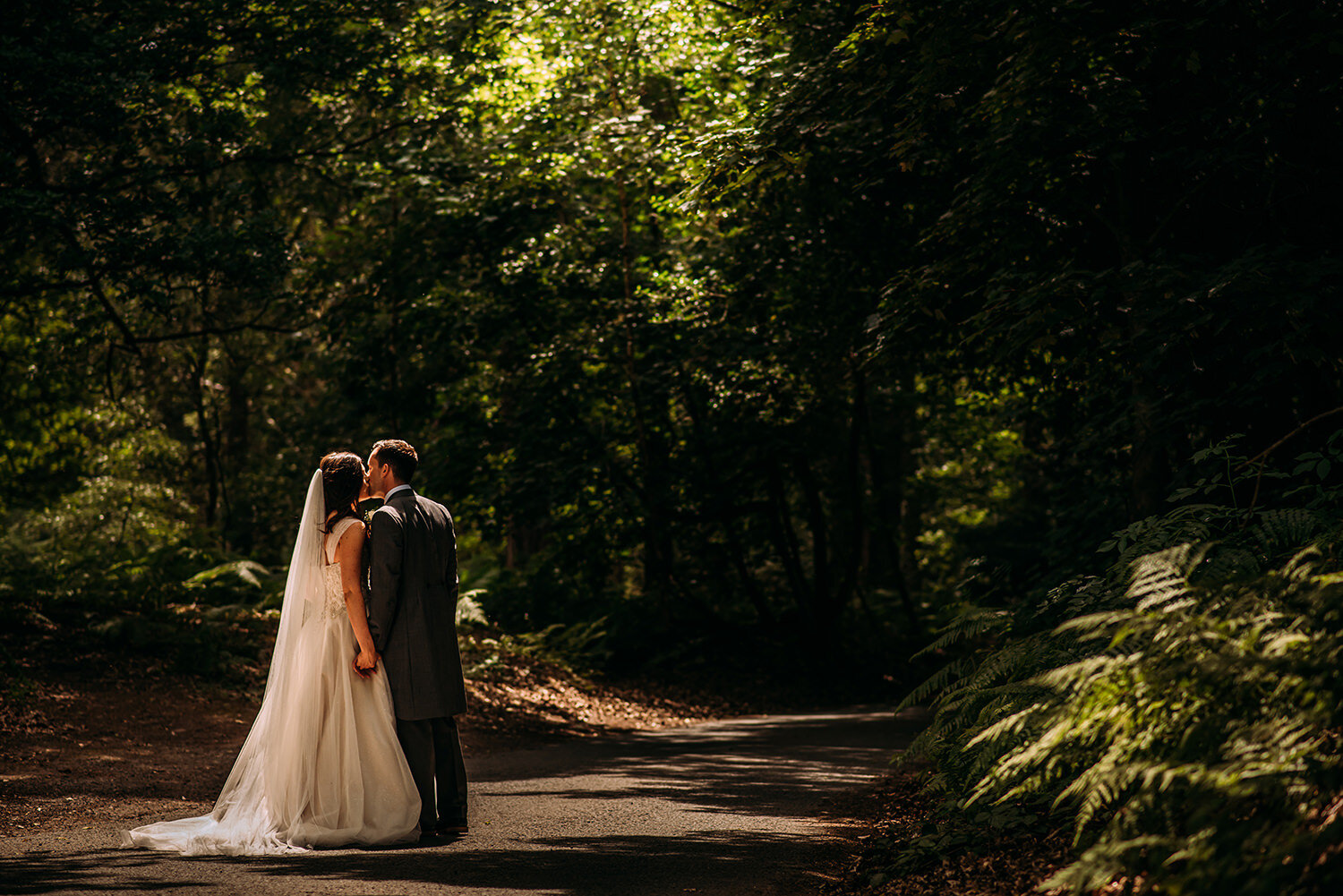  Bride and groom kiss in the woods at Peckforton 