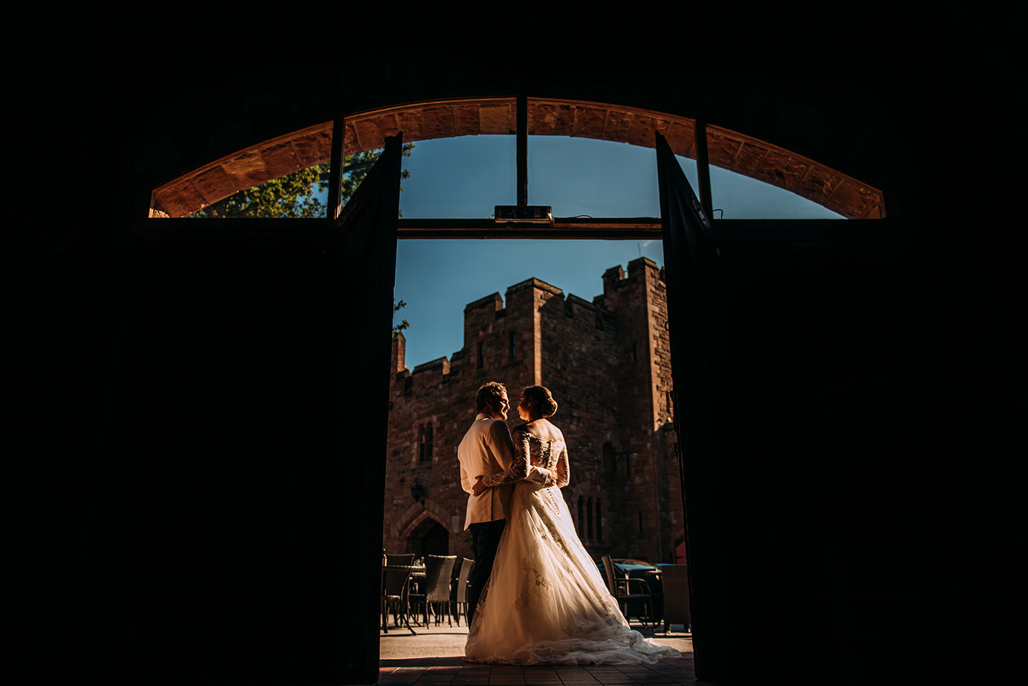  bride and groom framed by barn doors with castle behind 
