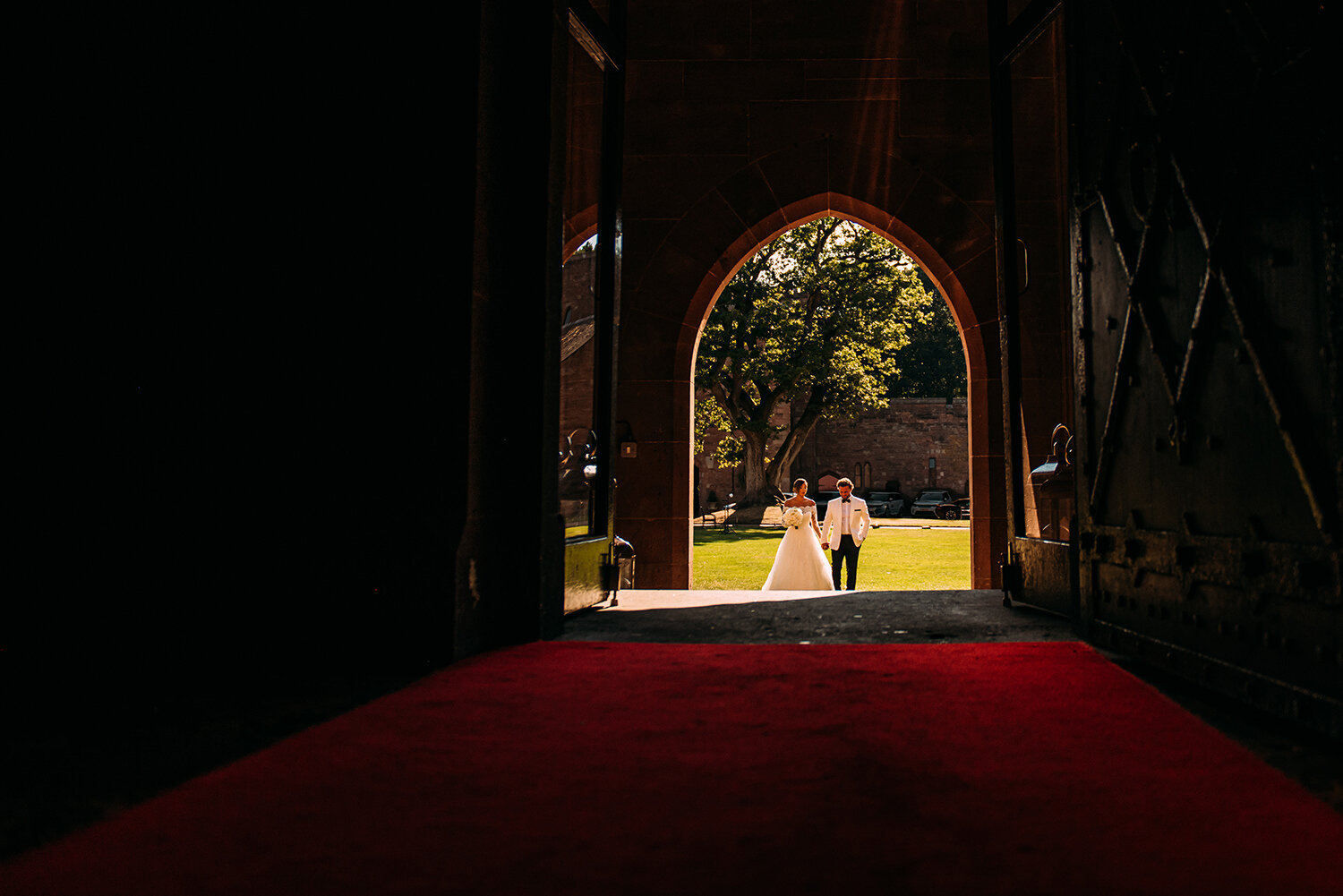  Bride and groom walking to the great hall, framed by the door way 