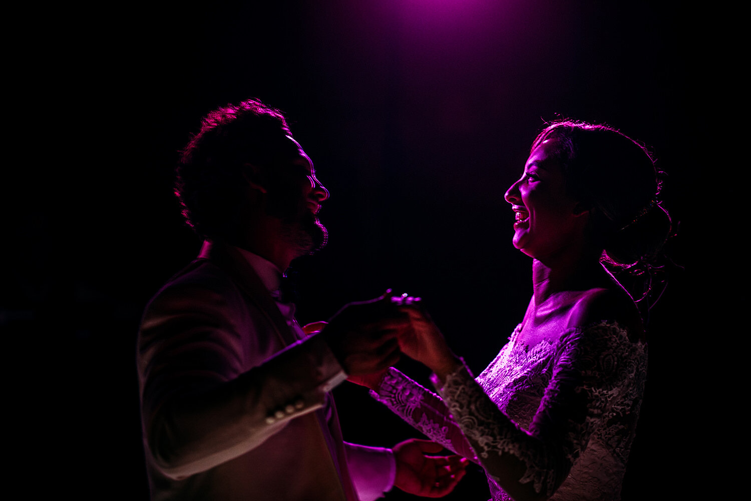  Bride and groom laughing under purple light. 