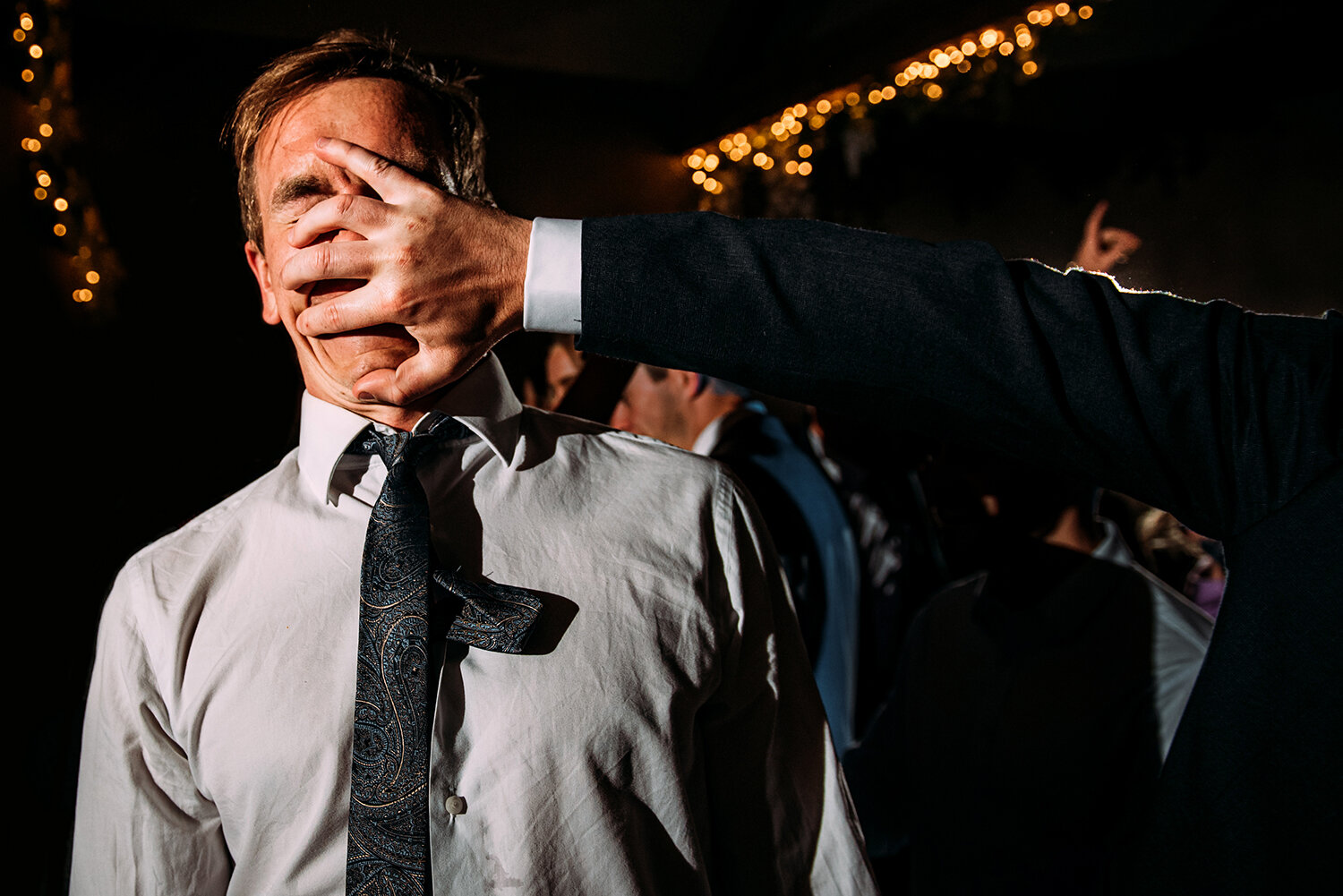  A hand on guests face on the dance floor. 