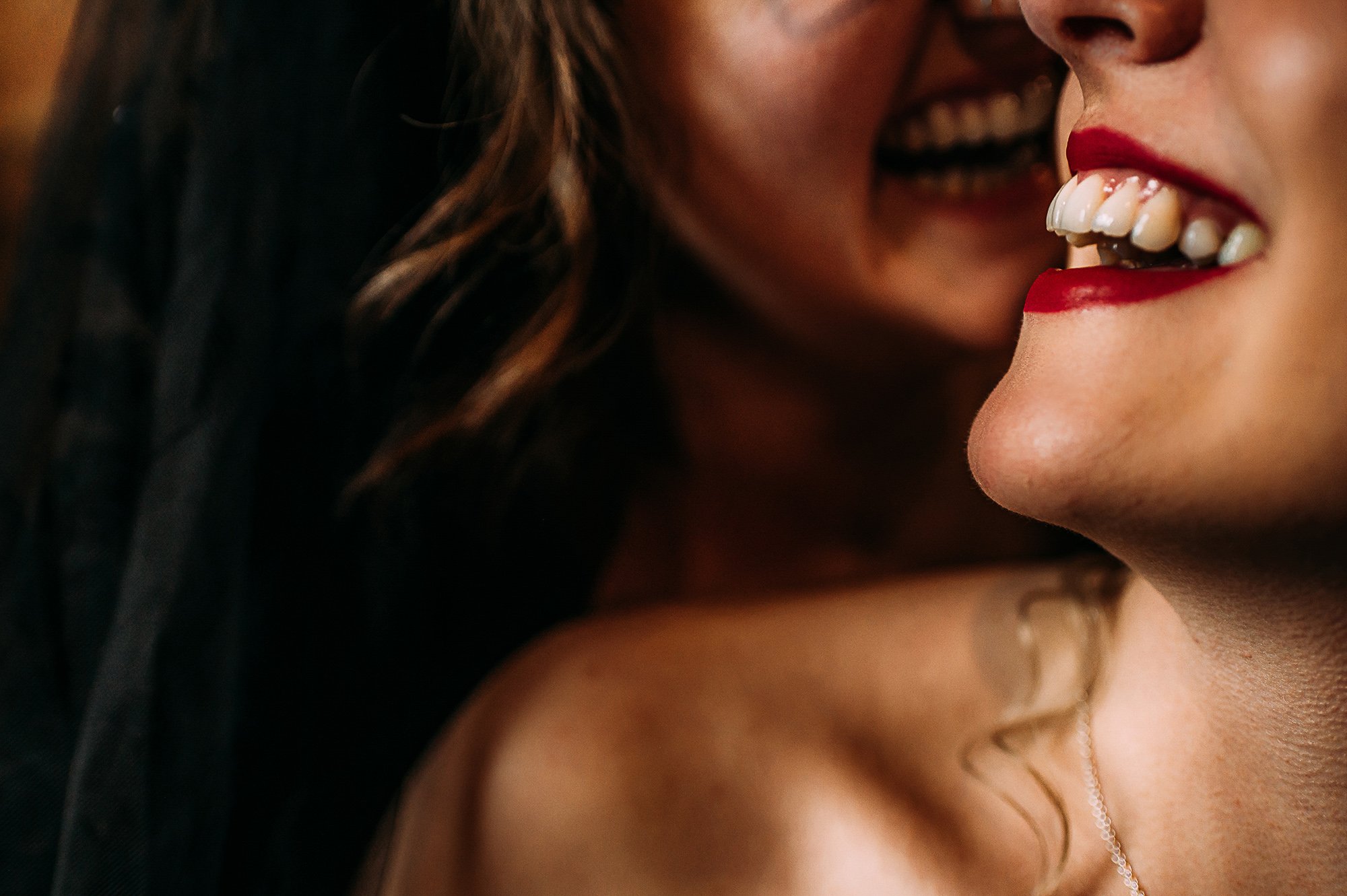  Close up on the smiling mouths of two brides. 