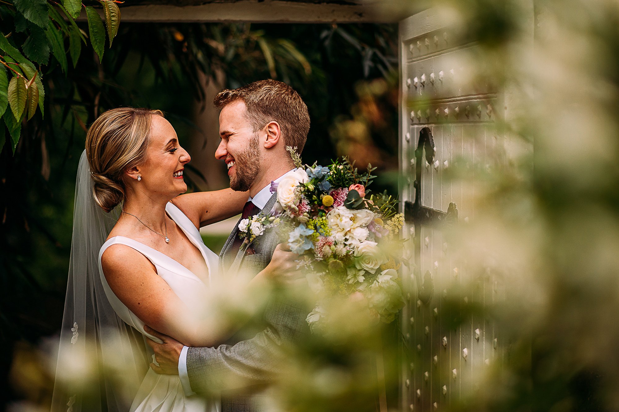  Couple portrait in a door way shot through flowers. 