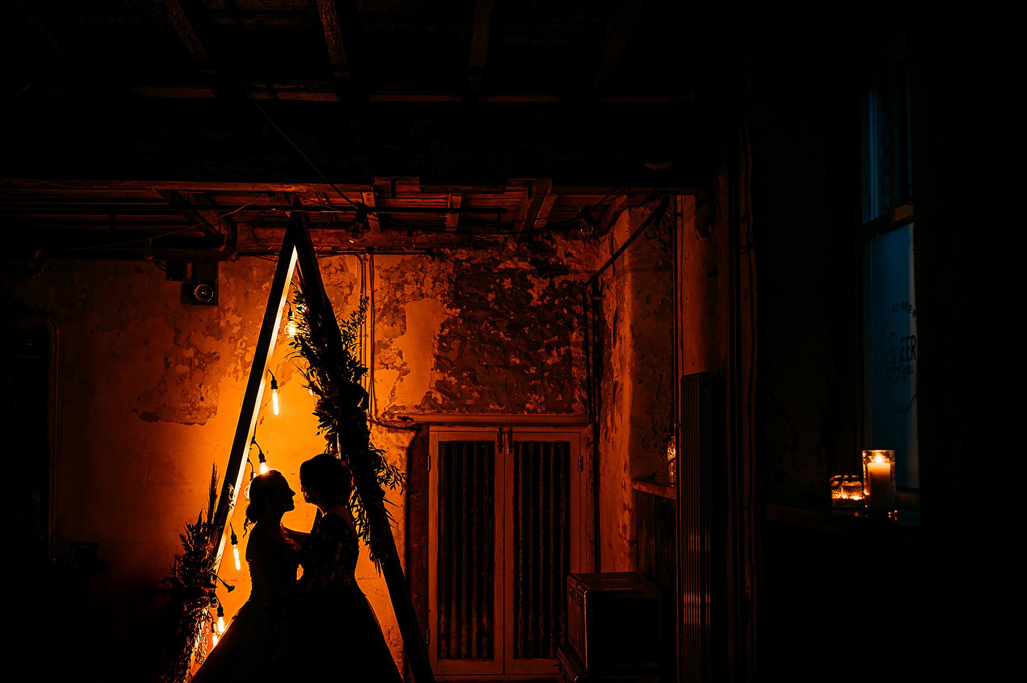  Bride and bride silhouette by an orange light.  