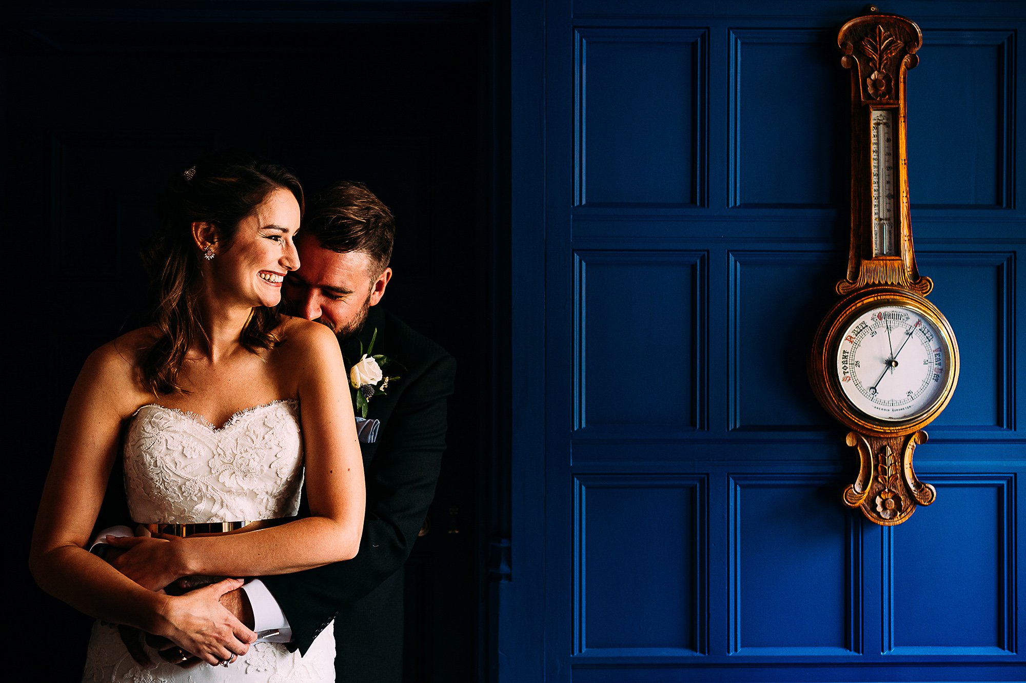  Couple portrait by a blue wall with an old clock. 