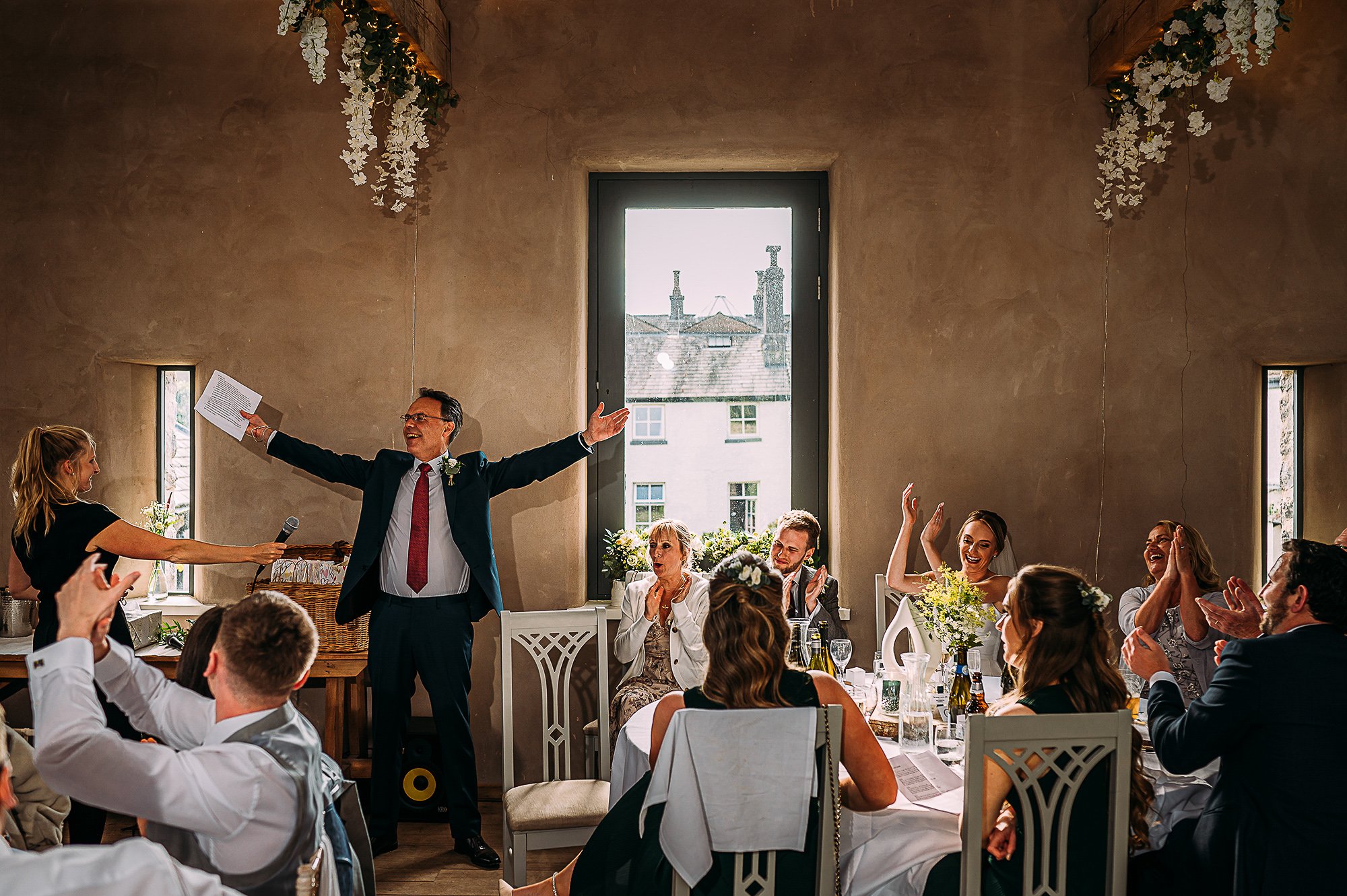  Father of bride holding out his arms as he starts his speech. 