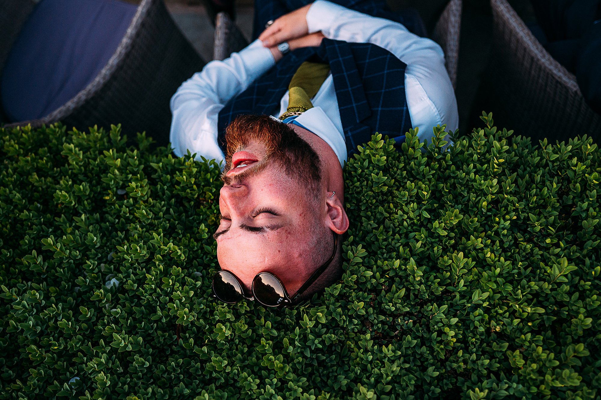  Drunk guest asleep with his head on a bush. 