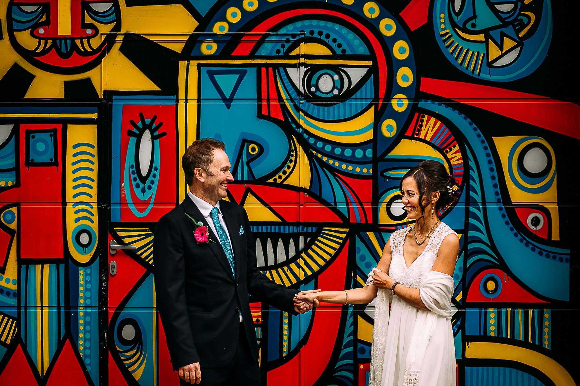  Couple stood in front of a cool street art wall. 