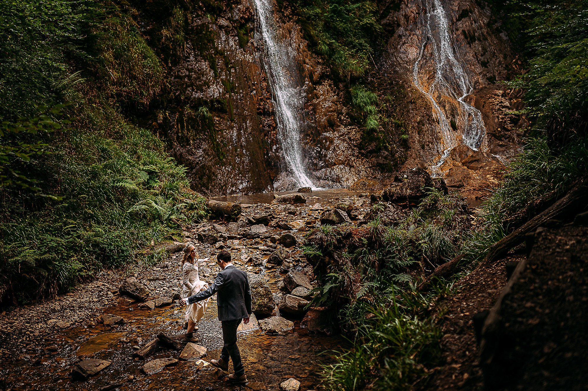  Bride and Groom walking down to a waterfall. 