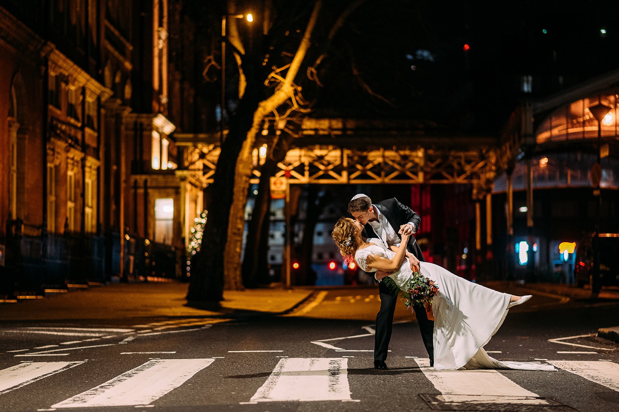  Groom dips wife for a kiss on a zebra crossing at night. 