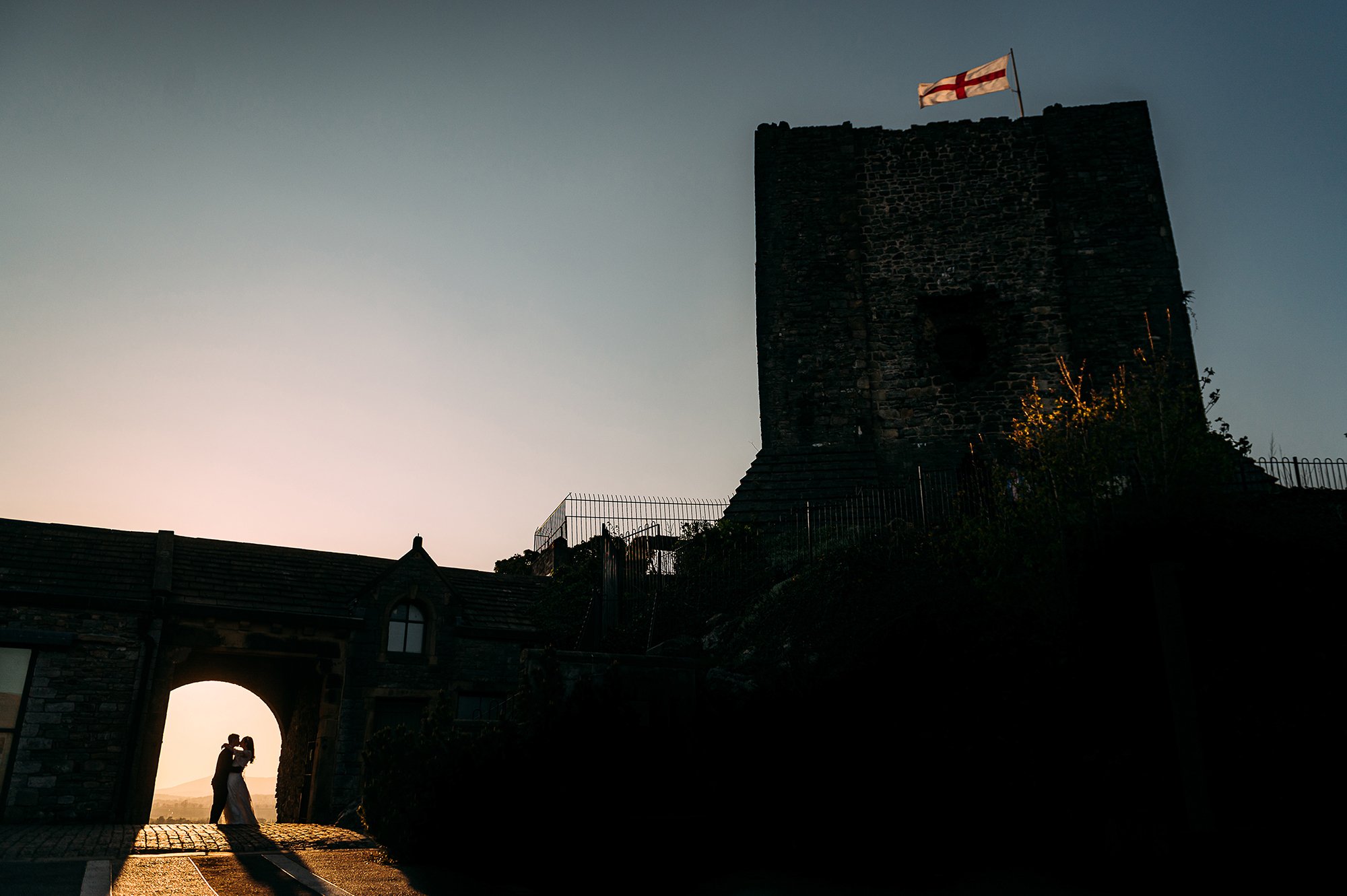  Bride and groom kiss in the arch of Clitheroe castle. 