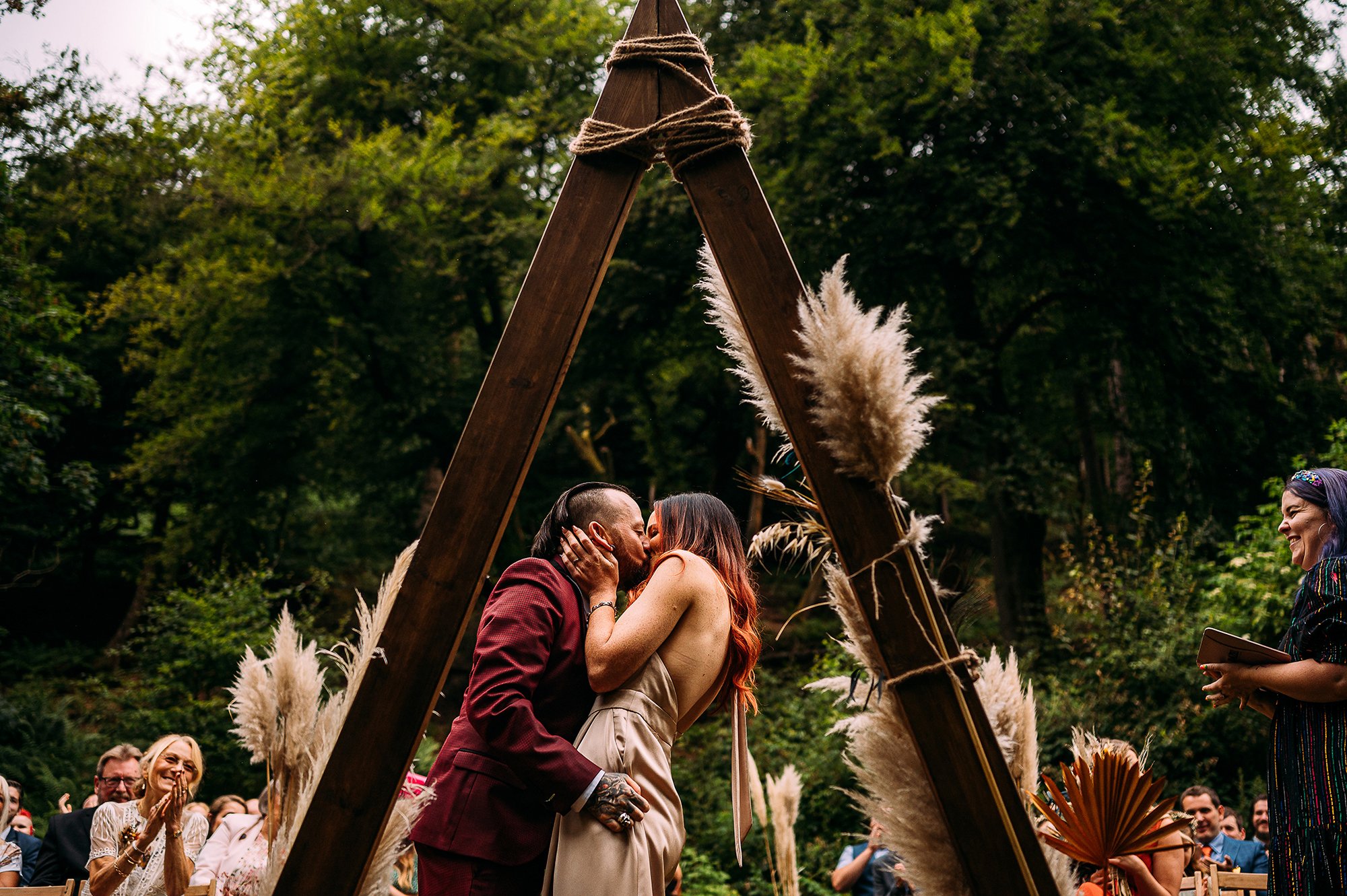  First kiss under a triangular structure at an outdoor ceremony. 