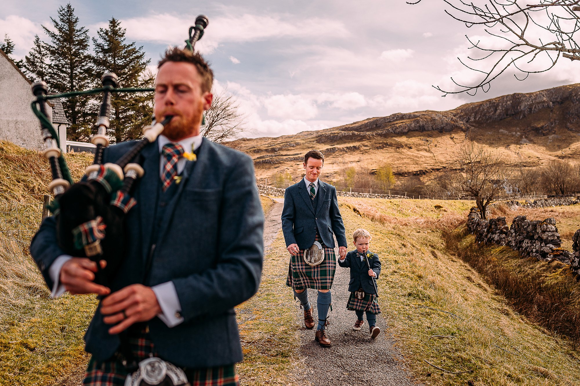  Groom walking with son and brother to church. They are playing bag pipes and a flute. 